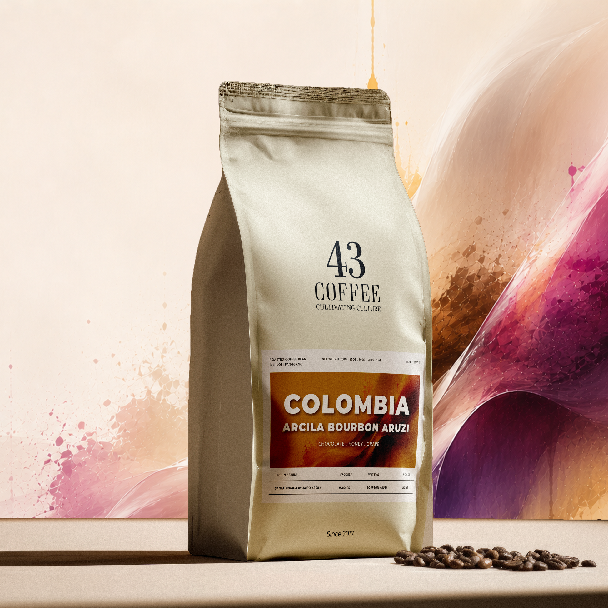 A 43 Coffee bag of Colombia Arcila Bourbon Aruzi coffee stands on a light surface with scattered coffee beans in front. The packaging is cream-colored with a prominent orange-brown label, set against a stylized, abstract background with pink, purple, and beige tones.