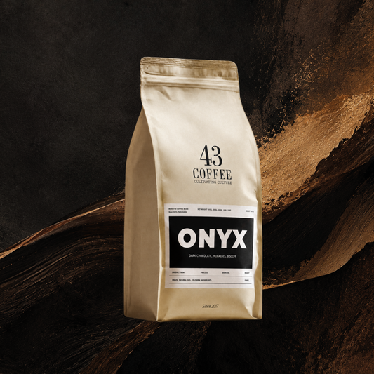 A 43 Coffee Onyx dark chocolate medium roast coffee bag, standing upright against a dark textured background with a gold leaf accent.